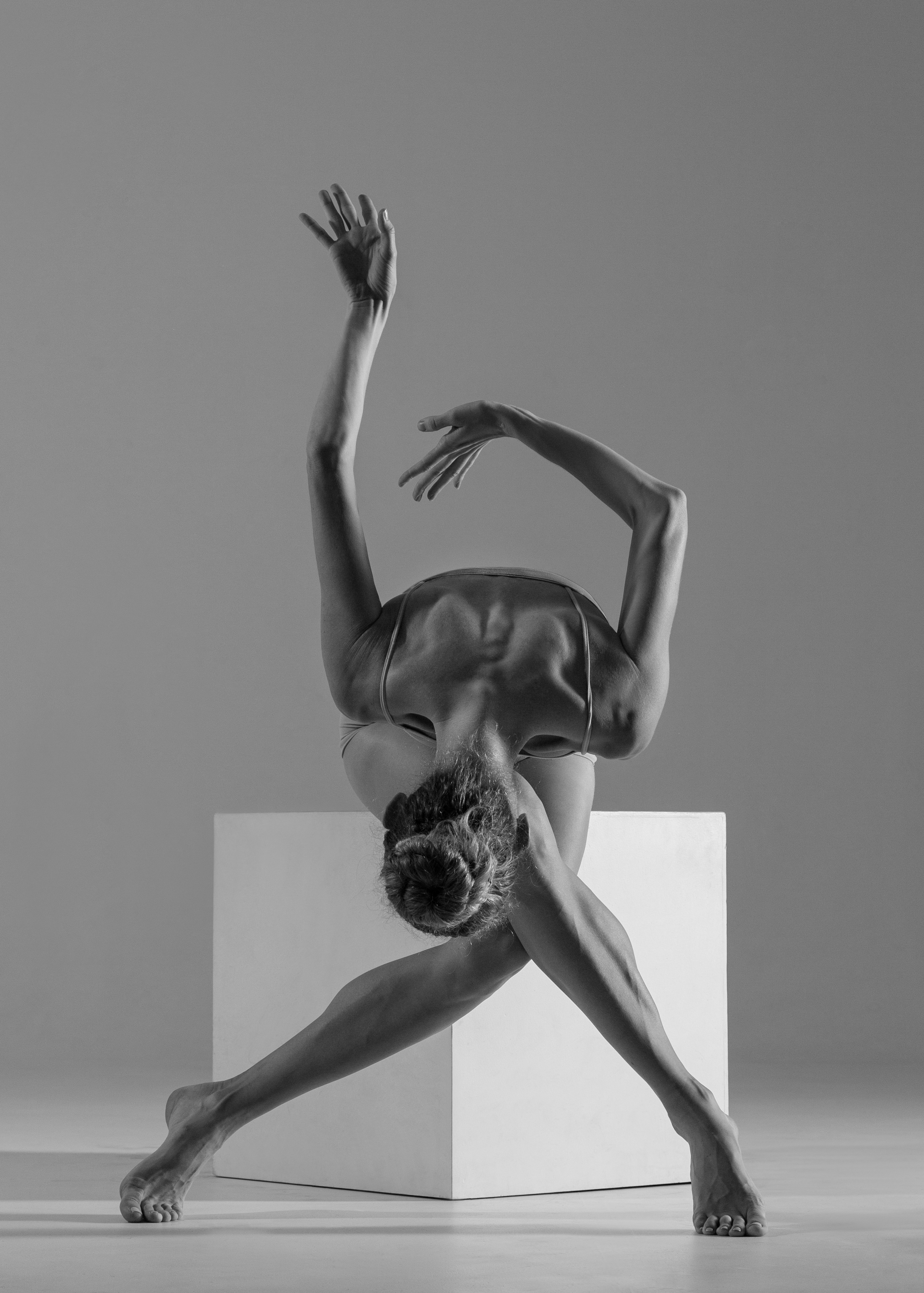 A ballerina in a leotard in front of a cube in a graphic pose